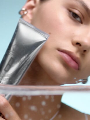 Model holding Lathering Tube Soap against her clean face